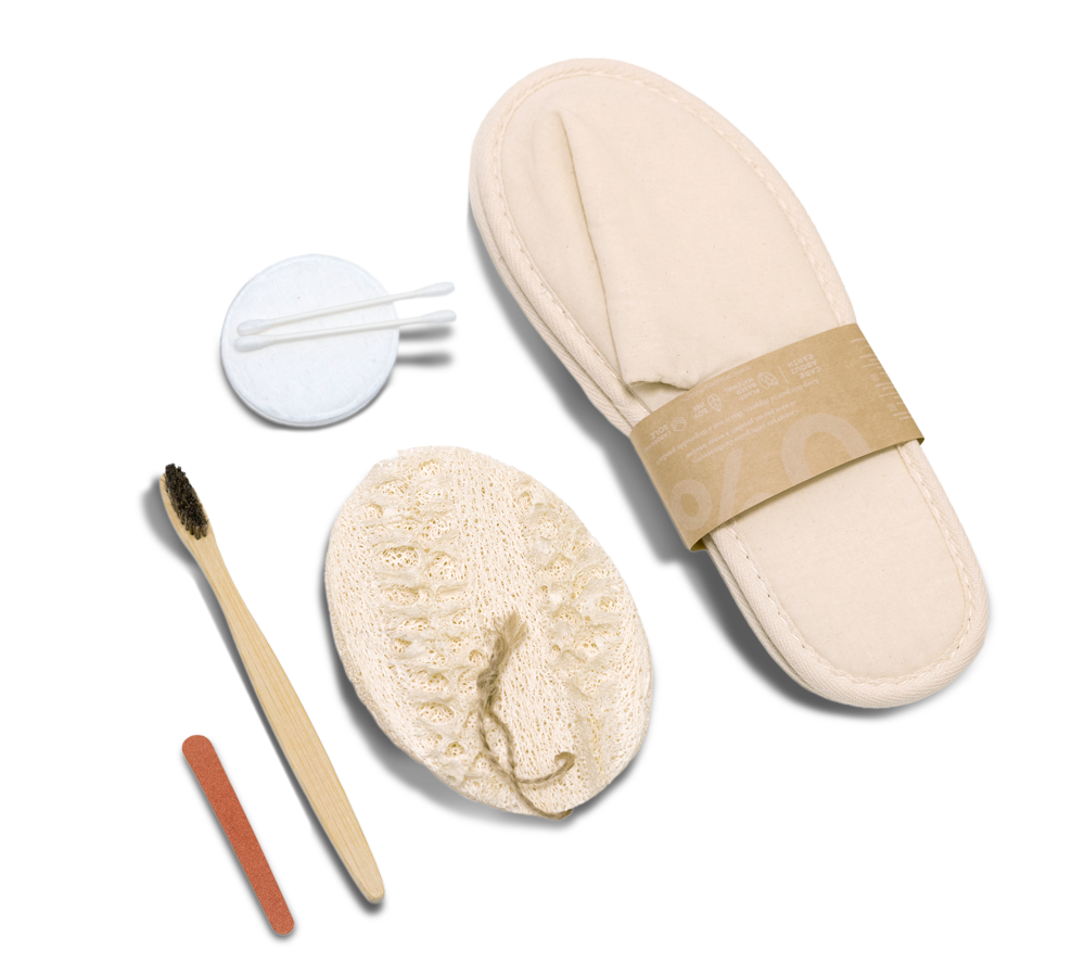 Um conjunto de spa composto por um chinelo bege, um pequeno frasco, uma escova de dentes, uma bucha vegetal e uma lima de unhas, dispostos de forma organizada.