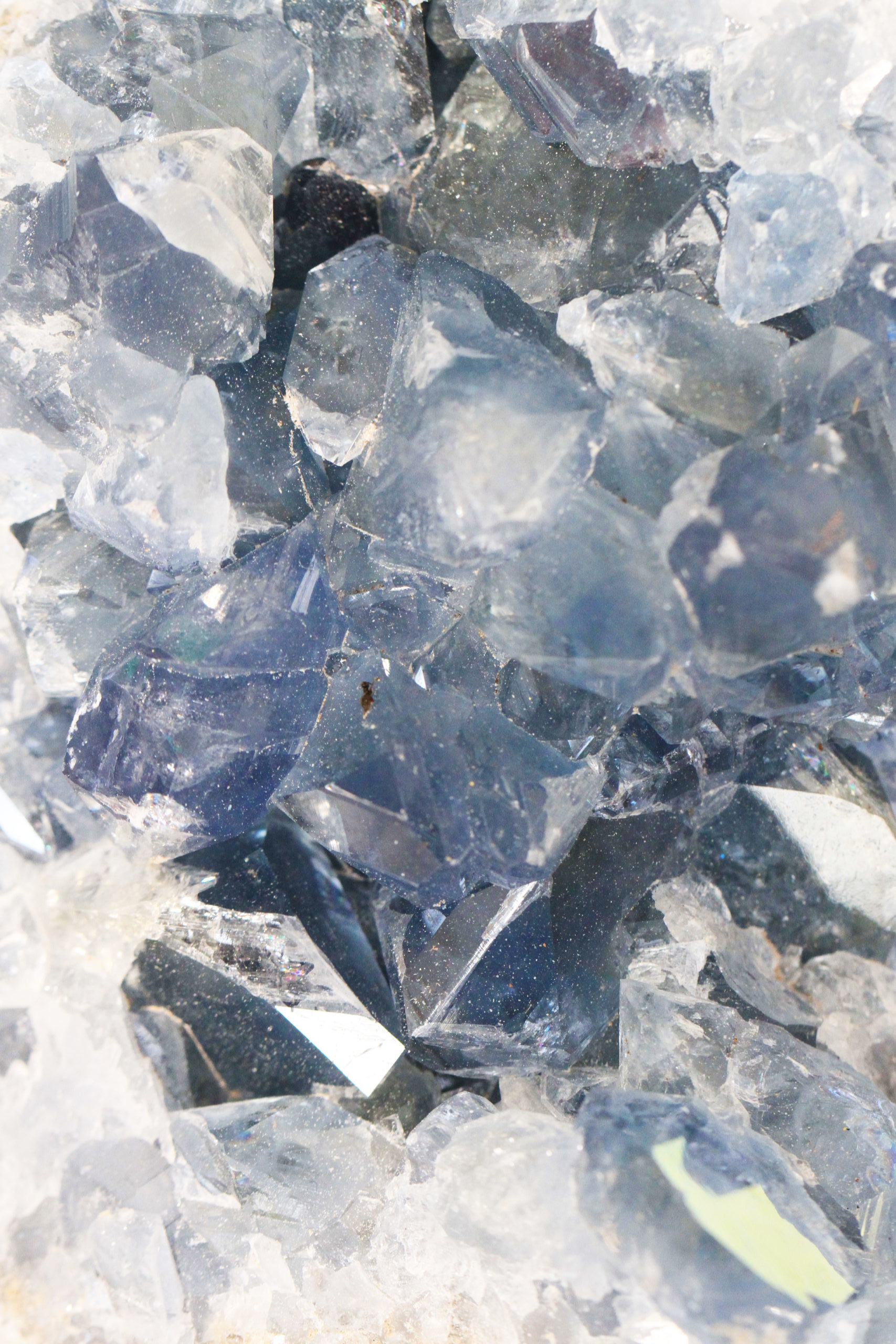 Nahaufnahme von gezackten blauen Kristallen mit funkelnder Textur, chaotisch angeordnet vor einem hellen Hintergrund.
