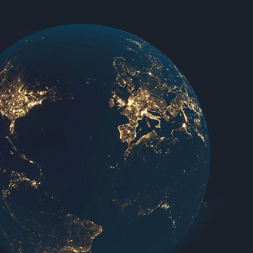 Uma vista da Terra a partir do espaço, iluminada pelas luzes das cidades à noite, mostrando a Europa e partes da Ásia. A imagem tem um fundo escuro, destacando as áreas brilhantes de atividade humana.