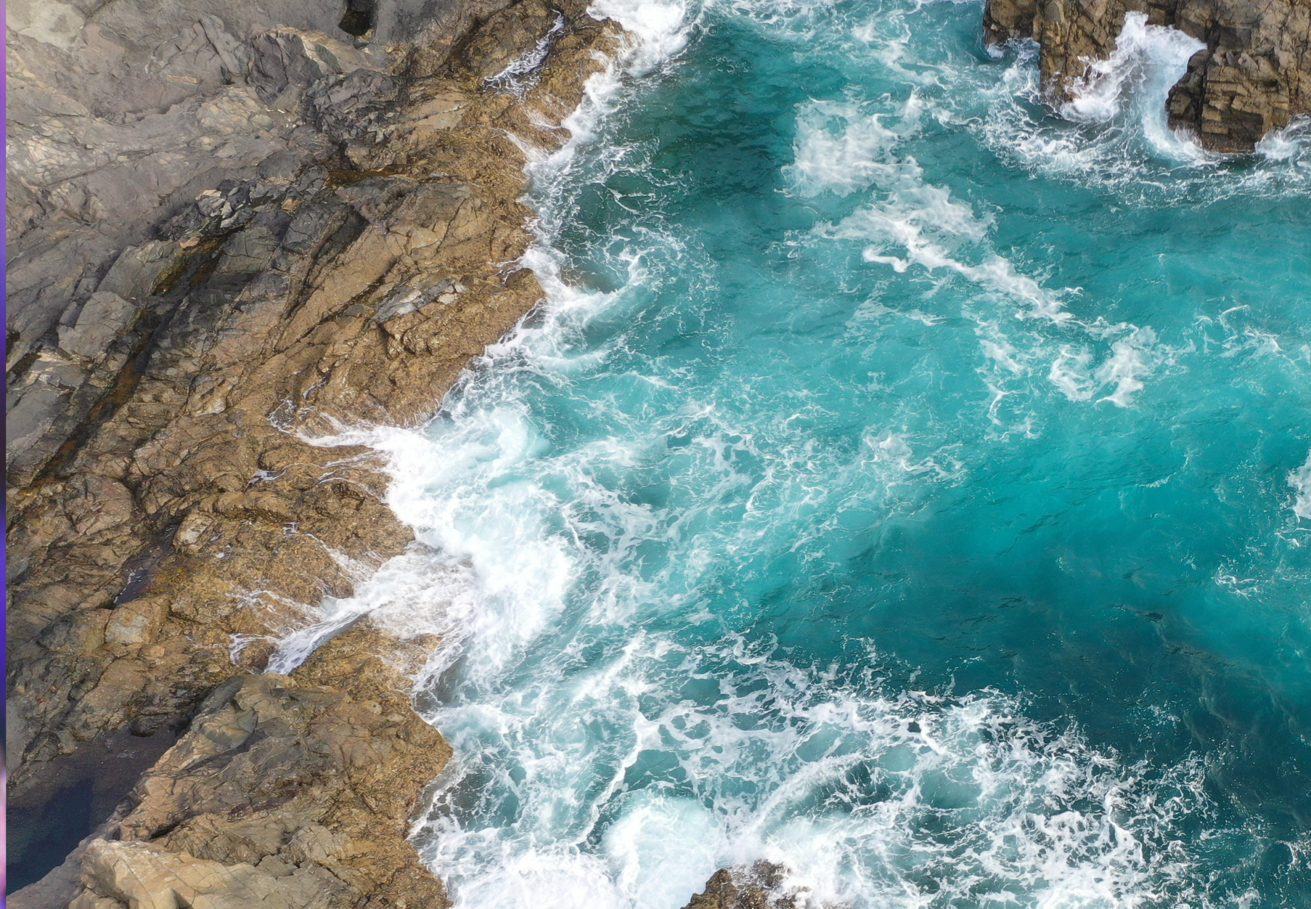 Vista aerea delle onde che si infrangono contro le formazioni rocciose lungo una costa turchese.