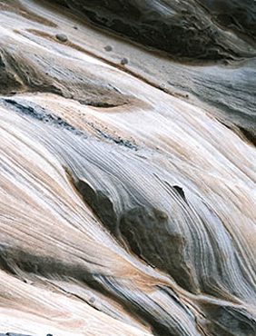Abstracte patronen van wervelende bruine, grijze en witte tinten doen denken aan stromend water of gemarmerde texturen.