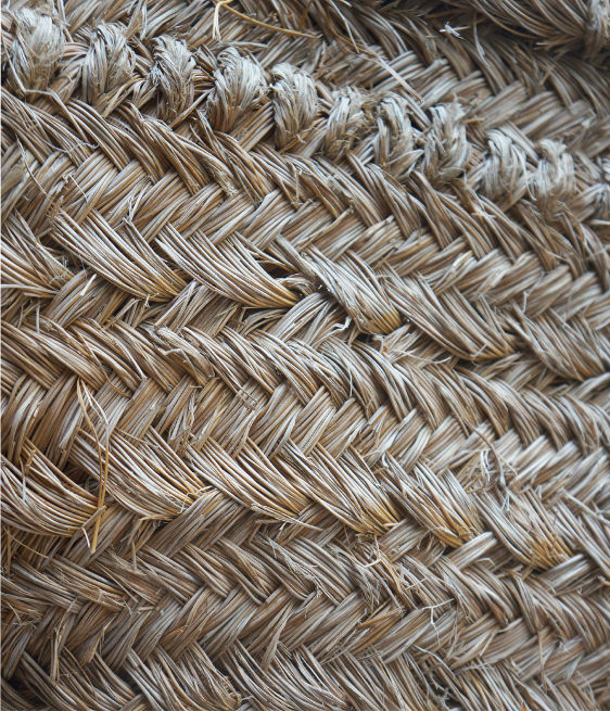 Primo piano di fibre naturali intrecciate, che mostrano motivi e trame intricati nei toni del beige e del marrone chiaro.