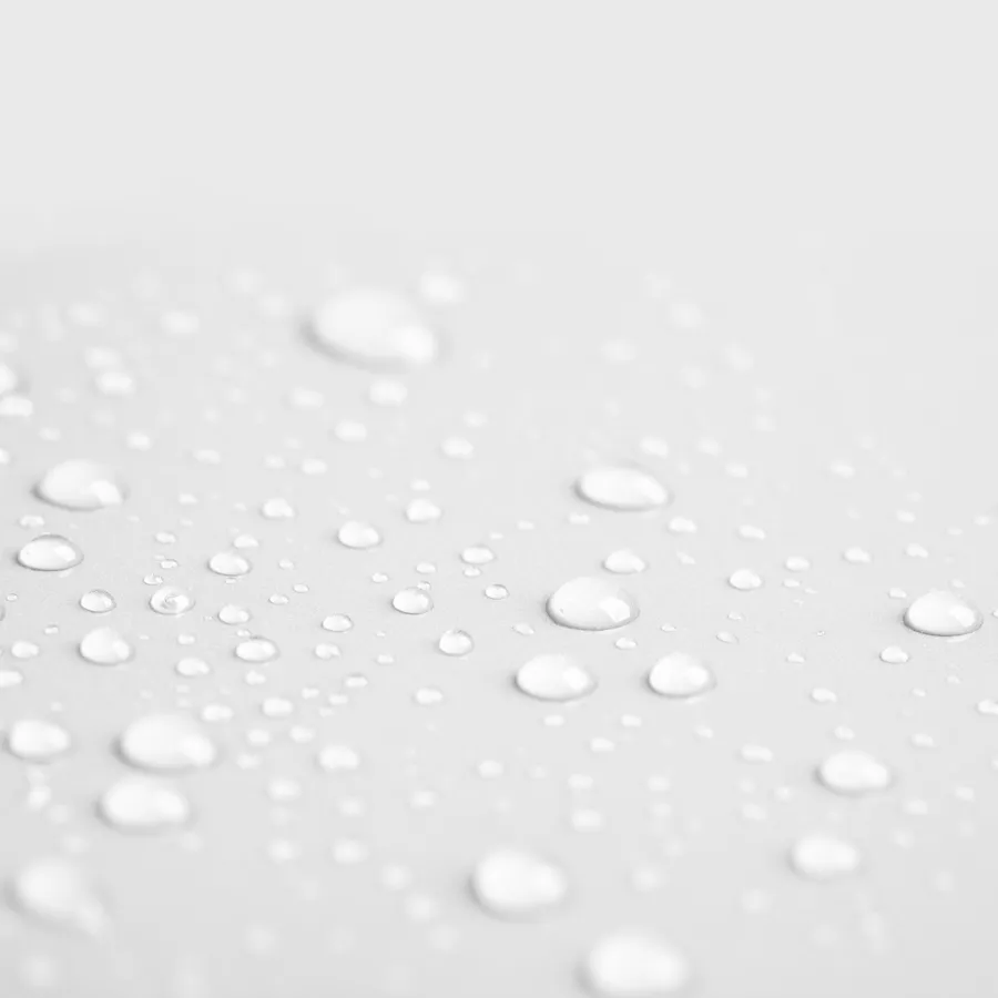 Nahaufnahme von klaren Wassertropfen, die auf einer hellgrauen Oberfläche verstreut sind und eine weiche, glatte Textur bilden.
