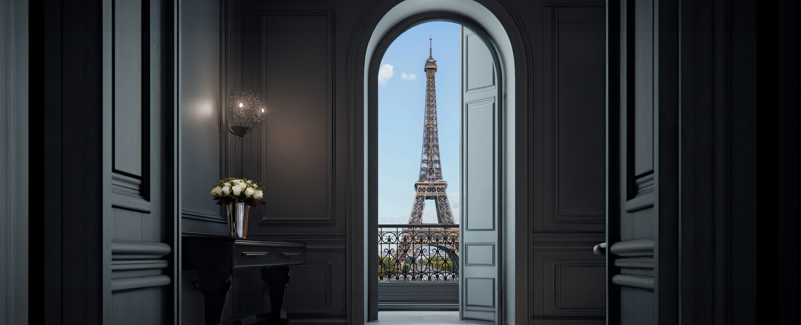 Vista de um quarto elegante através de uma porta em arco aberta, com varanda com corrimão elegante e vista panorâmica da Torre Eiffel ao fundo.