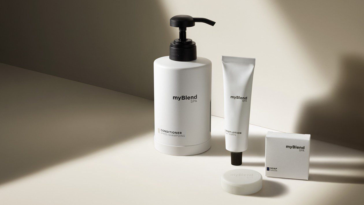 Una composizione minimalista di myBlend SPA , tra cui balsamo, lozione per il corpo e sapone, presentati in confezioni bianche con luci naturali soffuse e ombre su uno sfondo neutro.