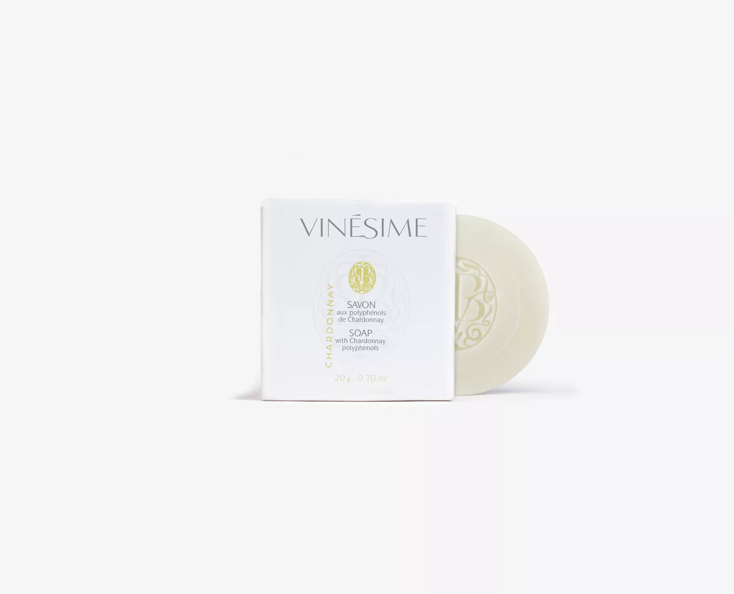 Uma barra de Vinésime numa caixa branca com um design minimalista, apresentando o nome da marca e os detalhes do produto numa tipografia elegante. O sabonete tem uma forma redonda e é exibido ao lado da caixa.