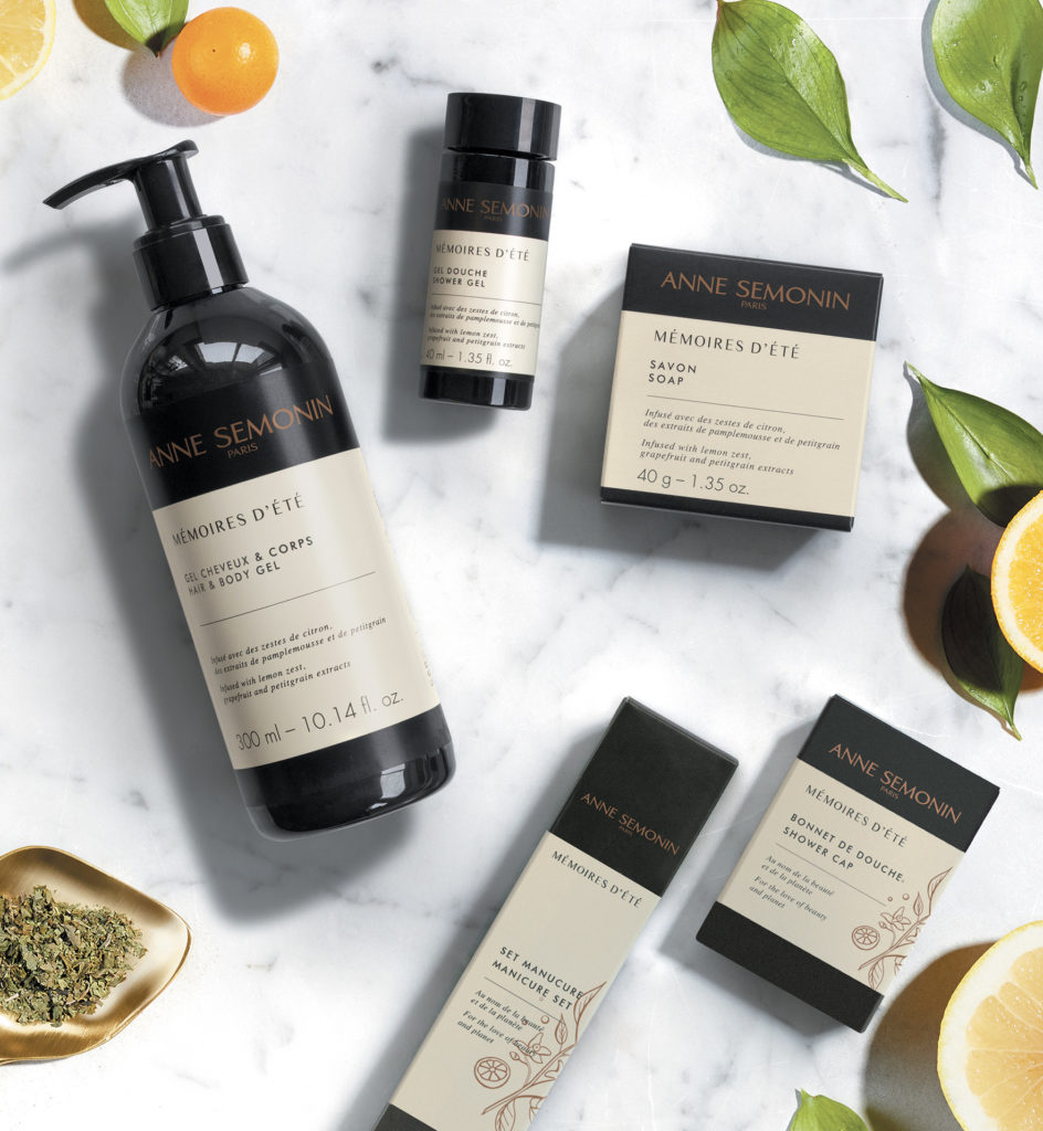 Uma variedade de produtos para a pele da Anne Semonin, incluindo um gel corporal, sabonete e outros itens embalados, expostos sobre uma superfície de mármore com rodelas de laranja e folhas verdes.