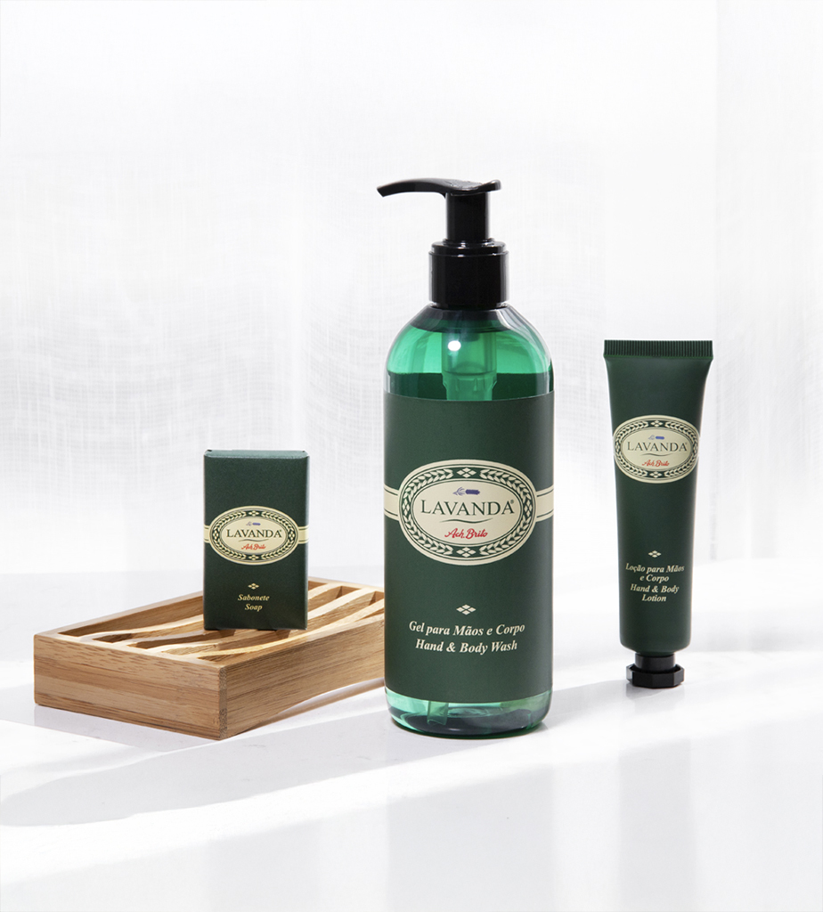 Set di prodotti per la cura personale al profumo di lavanda composto da un flacone grande di detergente per mani e corpo, una piccola saponetta e un tubetto di crema idratante, presentati su un vassoio di legno. Gli articoli sono racchiusi in un'elegante confezione verde con un'etichetta in stile vintage.