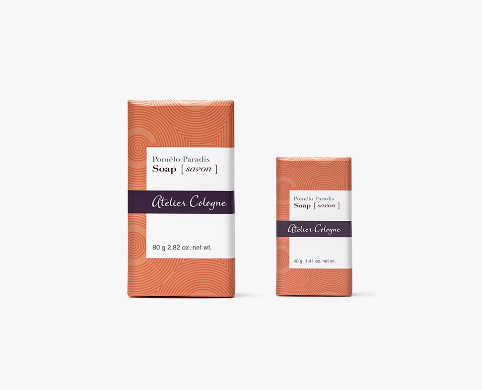 Zwei Seifenstücke von Atelier Cologne, eines größer (80 g) und eines kleiner (40 g), mit orangefarbenem geometrischem Design und weißen Etiketten.