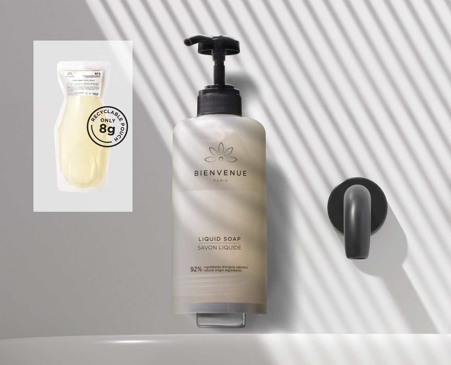 Eine Pumpflasche mit Bienvenue steht auf einem Waschbecken mit Schattenmuster, daneben ein Verpackungsetikett, das darauf hinweist, dass sie recycelbar ist und 86 Gramm wiegt.