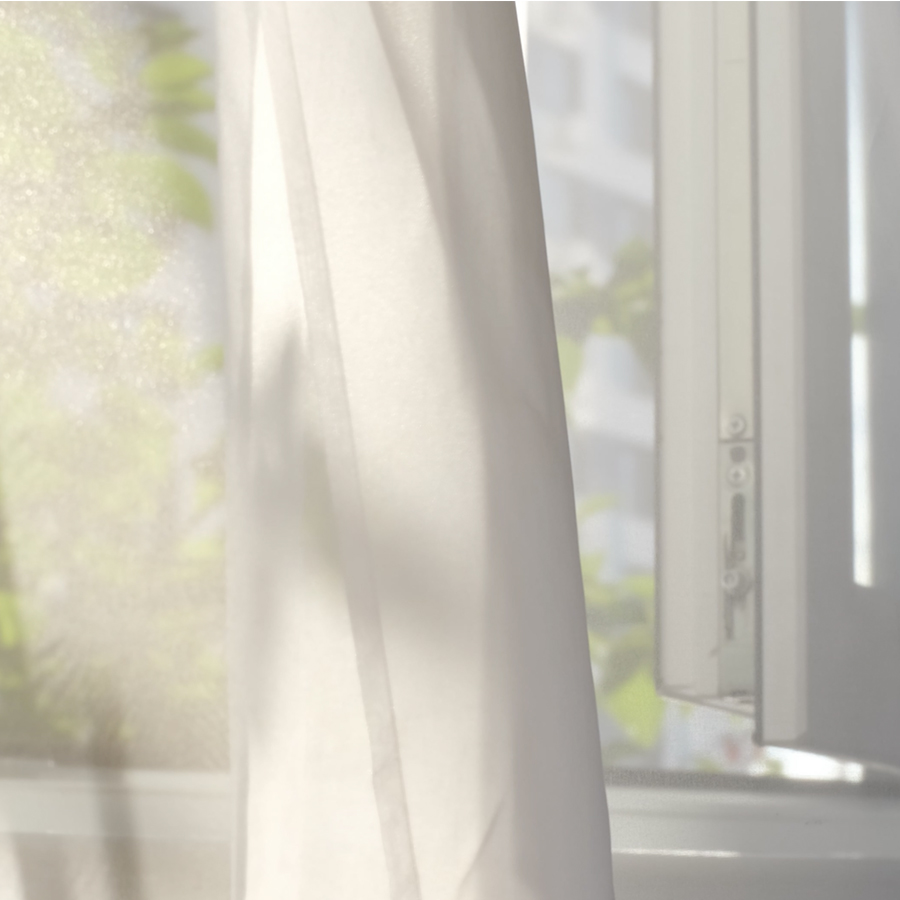 Ein durchsichtiger weißer Vorhang hängt sanft vor einem offenen Fenster und lässt sanftes Licht herein, wodurch eine ruhige Atmosphäre entsteht.