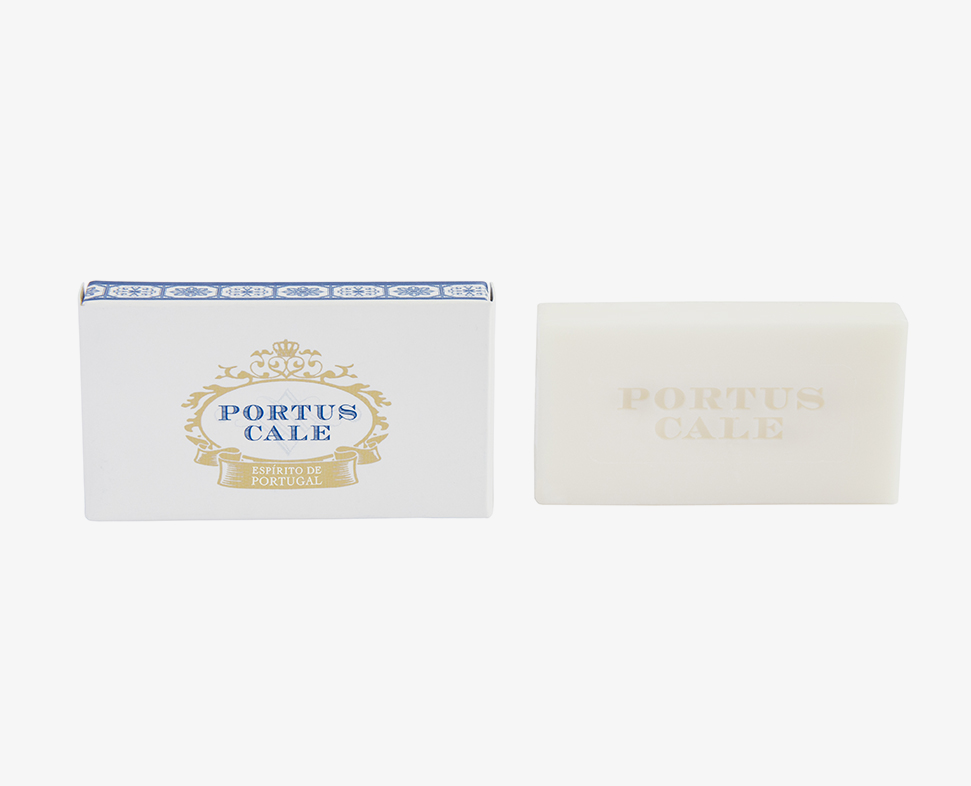 Una saponetta bianca con la scritta "PORTUS CALE" in rilievo, accompagnata da una confezione decorativa con lo stesso nome e un disegno blu e oro.