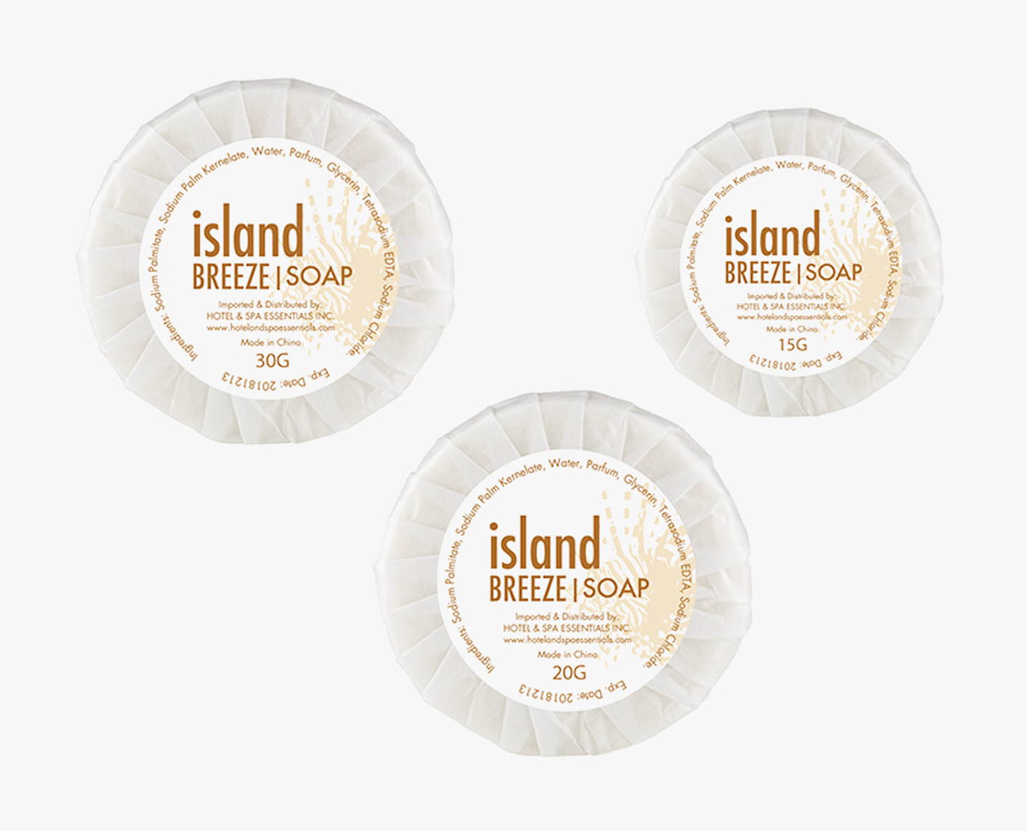 Τρία κυκλικά σαπούνια με την ένδειξηIsland Breeze » σε διάφορα μεγέθη (30 g, 20 g και 15 g), τυλιγμένα σε λευκό χαρτί με διακοσμητικό λογότυπο.