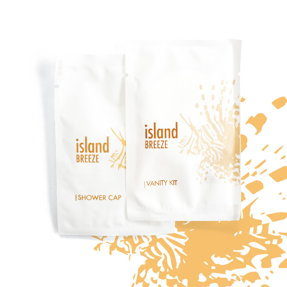 Δύο λευκά πακέτα με την ένδειξηisland BREEZE και πορτοκαλί λεπτομέρειες, το ένα για σκουφάκι μπάνιου και το άλλο για σετ περιποίησης, με ελαφρύ αφηρημένο σχέδιο στο φόντο.