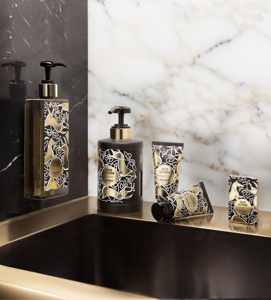 Eine Kollektion elegant gestalteter Hautpflegeprodukte mit Blumenmustern, präsentiert auf einer Marmorplatte neben einem eleganten Waschbecken.