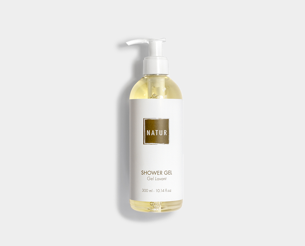 Flacone trasparente di gel doccia con erogatore a pompa, con l'etichetta "NATUR GEL", contenente un liquido giallo pallido. Il flacone ha una capacità di 300 ml (10,4 fl oz) e presenta un design minimalista.