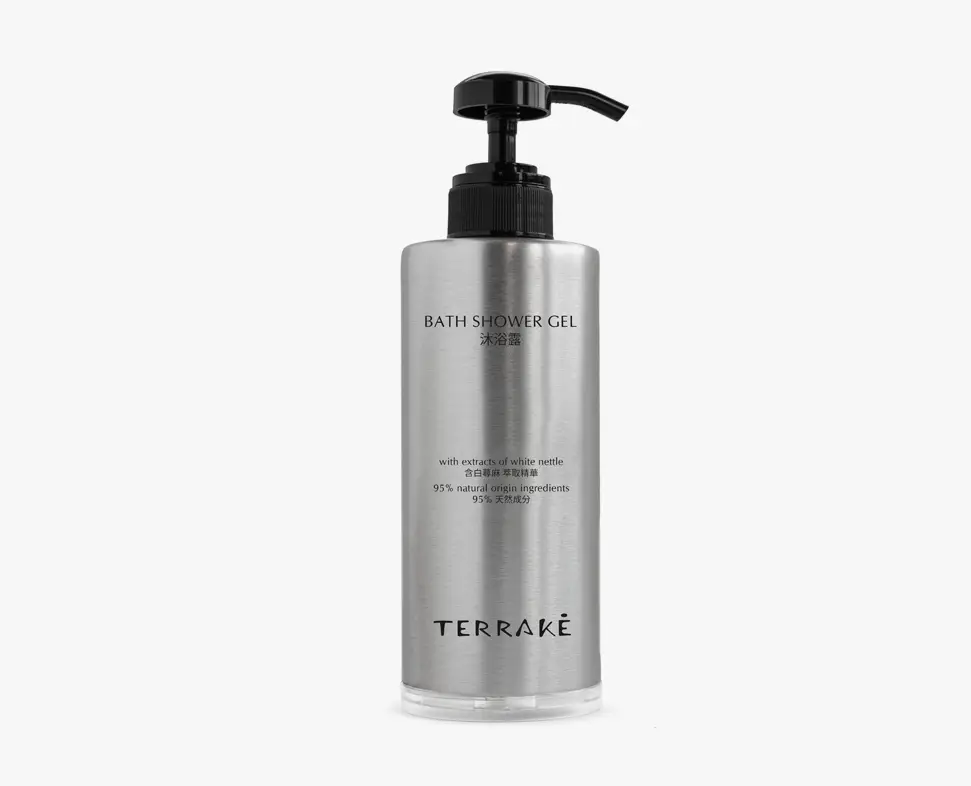 Flacone metallico di gel doccia con erogatore a pompa, recante il marchio "TERRAKE" e informazioni sui suoi ingredienti naturali. L'etichetta include testi in più lingue.