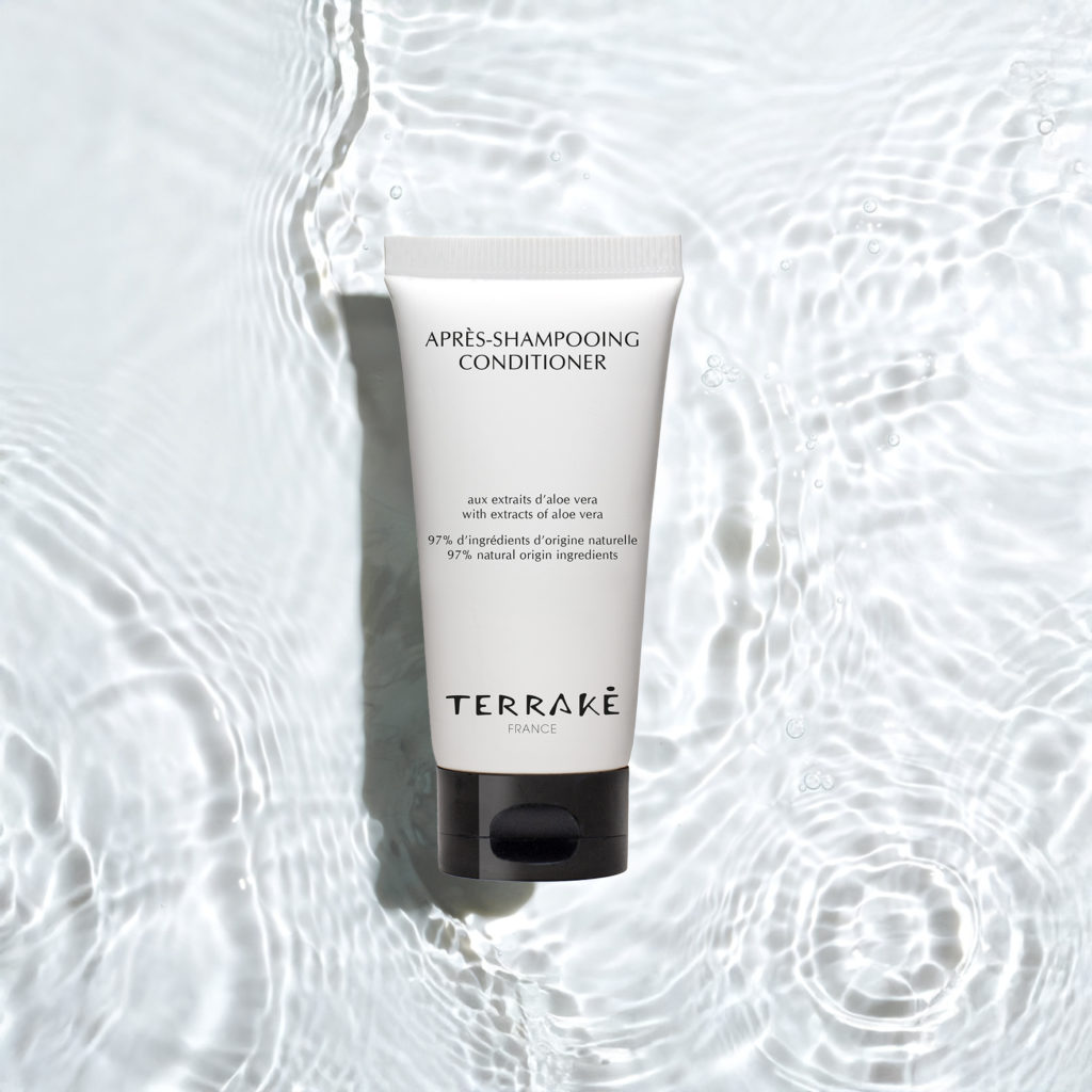 Un tubetto di balsamo Terrake con estratto di aloe vera, posizionato su una superficie ruvida che imita le increspature dell'acqua.