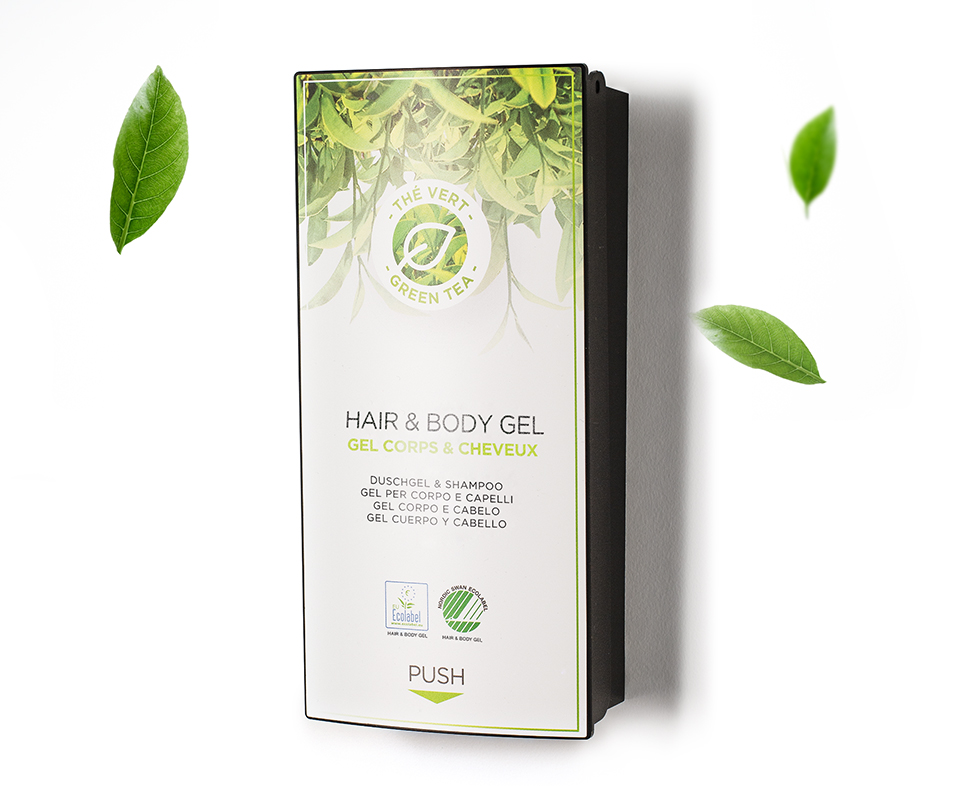 Um frasco de gel para cabelo e corpo com chá verde, com um design simples e minimalista, rodeado por folhas verdes. O rótulo destaca a sua dupla função como gel de banho e champô.