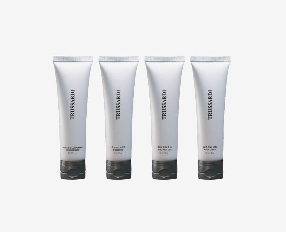 Vier Tuben Trussardi und Körperpflegeprodukte, darunter Shampoo, Conditioner und Gel, alle in eleganter, minimalistischer Verpackung.