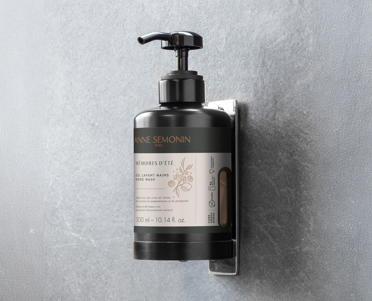 Um frasco preto com bomba para lavagem das mãos montado na parede, com um rótulo que diz «Mémoires d'Été» de Anne Semonin, com um design elegante e moderno contra um fundo cinzento texturizado.