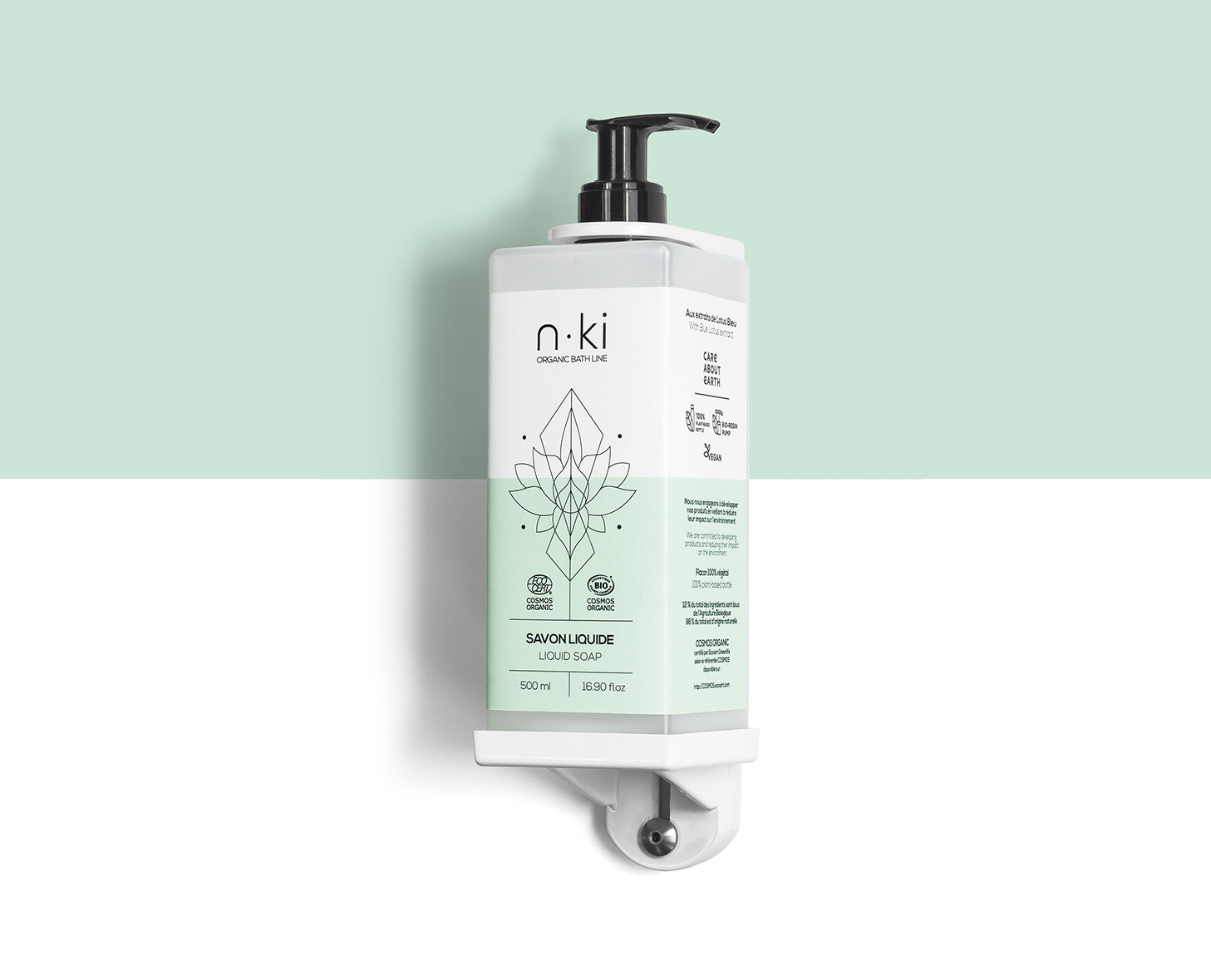 Eine Pumpflasche mit n-ki Flüssigseife in minimalistischem Design, mit einer Farbgebung in Grün und Weiß und botanischen Illustrationen. Die Flasche ist an einer Wand befestigt, was ihre moderne und klare Ästhetik unterstreicht.