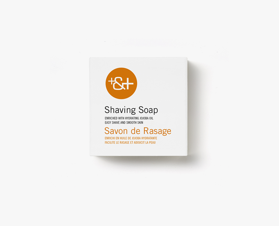 Eine weiße Schachtel mit Rasierseife mit der Aufschrift „Shaving Soap“, angereichert mit Jojobaöl, mit einem orangefarbenen Logo und französischem Text.