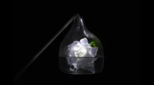 Un contenitore trasparente a forma di cupola riempito di cubetti di ghiaccio e illuminato dall'interno, su uno sfondo nero. Un tubo sottile fuoriesce dalla parte superiore del contenitore.