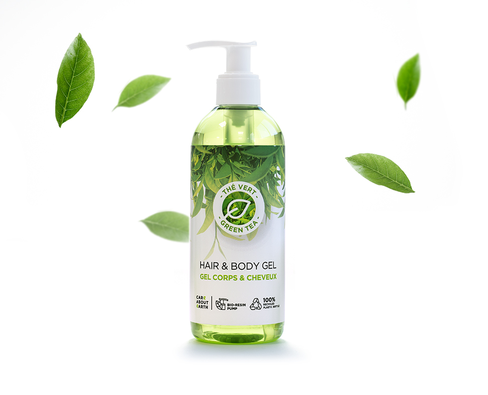 Um frasco transparente de gel para cabelo e corpo com um dispensador de bomba, rotulado como «The Very Green Tea» (O Chá Verde Muito Verde), rodeado por folhas verdes. O gel é de cor verde brilhante, dando uma aparência fresca e natural.