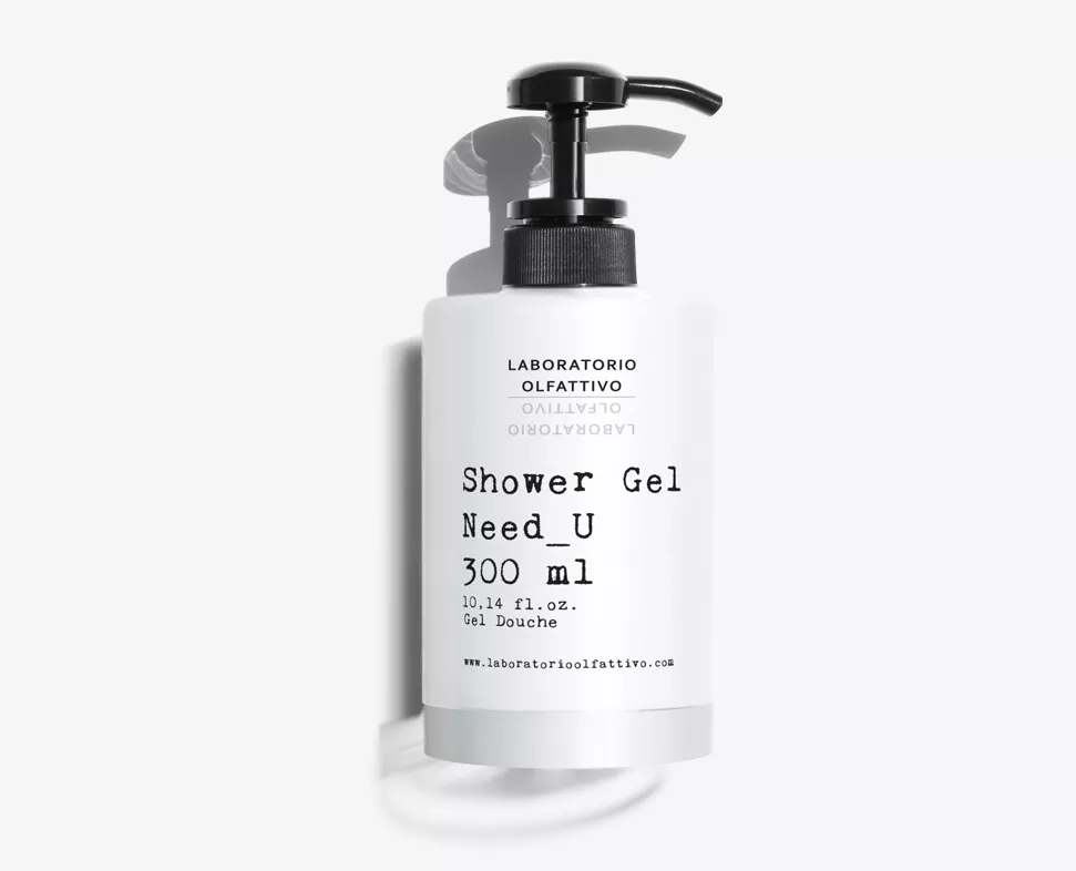 Flacone bianco di gel doccia con pompa nera, etichettato "Shower Gel Need_U" e contenente 300 ml. Il design presenta un testo minimalista e il marchio "Laboratorio Olfattivo".