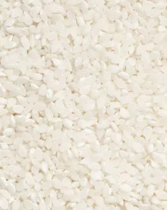 Um grande plano de uma superfície texturada coberta por pequenos grãos de arroz brancos.