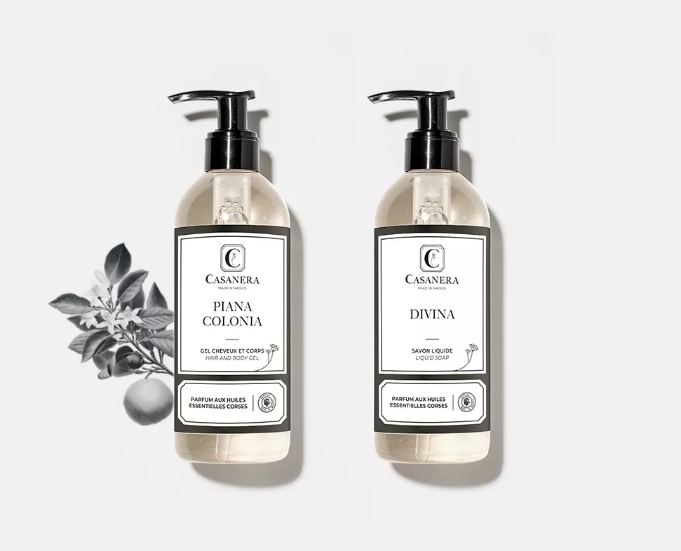 Zwei Flaschen Casanera mit den Bezeichnungen „Piana Colonia” und „Divina”, mit Pumpverschlüssen und minimalistischem Design, daneben eine botanische Illustration.