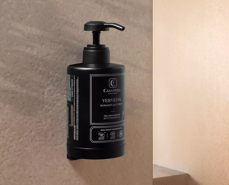 Eine dunkle Flasche Casanera Duschgel mit Pumpspender, angebracht an einer strukturierten Steinwand. Das Etikett ist mit weißer Schrift auf schwarzem Hintergrund versehen.