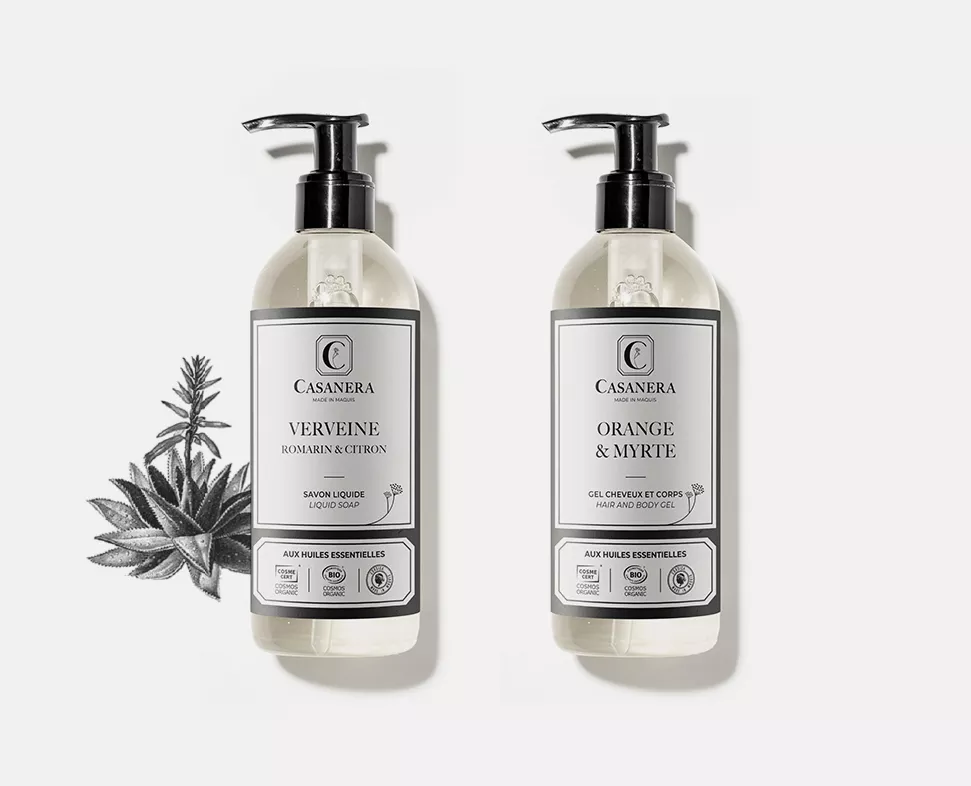 Zwei Flaschen Flüssigseife nebeneinander, beschriftet mit „Verveine Romarin &amp; Citron“ und „Orange &amp; Myrte“, mit einer Pflanzenillustration in der Ecke.