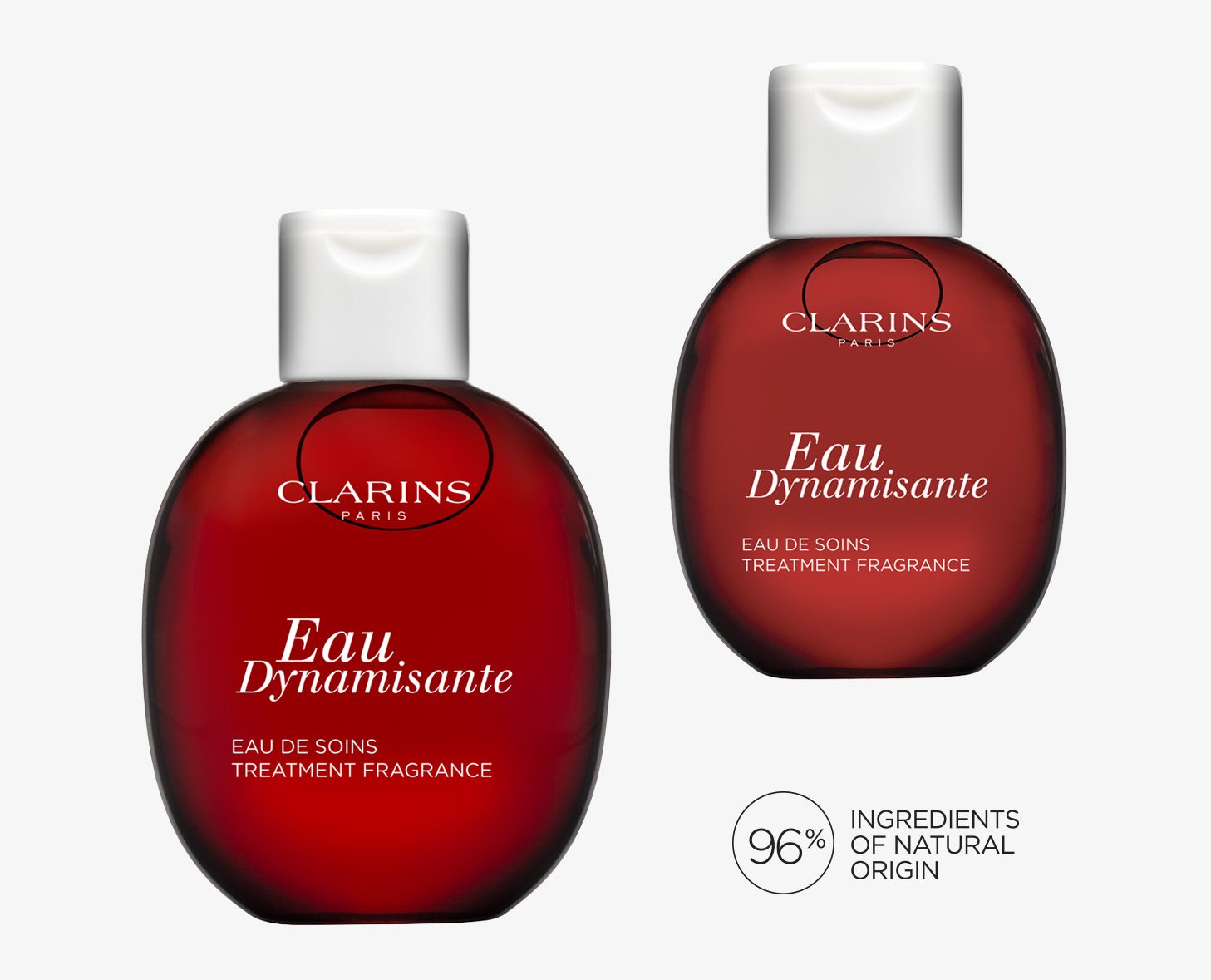 Zwei Flaschen Clarins Dynamisante Treatment Fragrance mit rundem, rotem Design und weißer Beschriftung. Eine Flasche zeigt das Frontetikett, die andere ist leicht gedreht und mit einem Hinweis auf 96 % natürliche Inhaltsstoffe versehen.