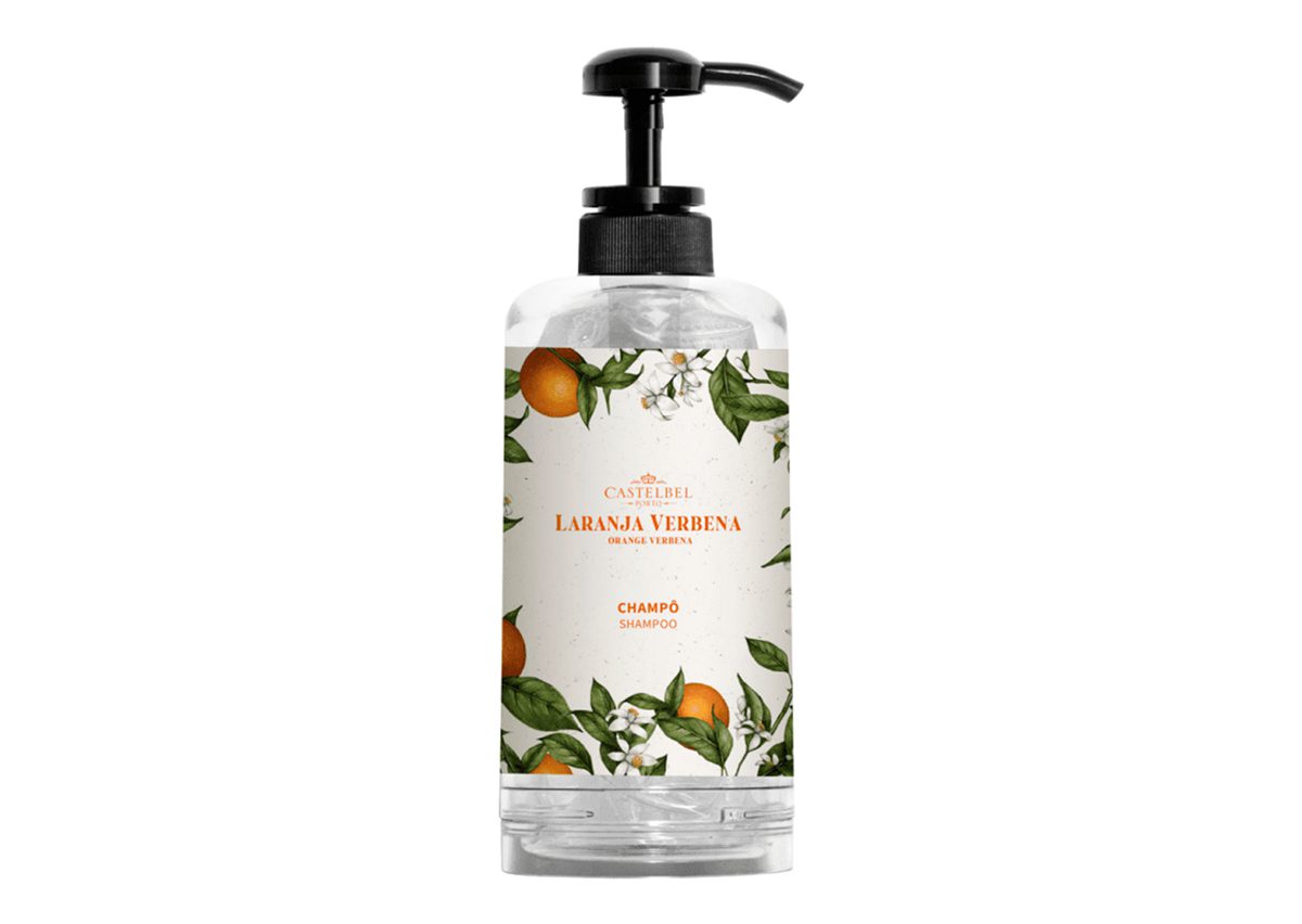Flacone trasparente di shampoo con erogatore a pompa, decorato con un'etichetta ornamentale raffigurante frutti arancioni e foglie verdi, con la scritta "Laranja Verbena".