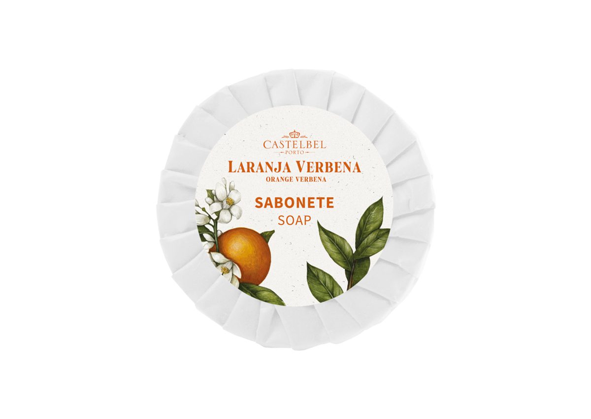 Una saponetta rotonda e bianca con un'etichetta decorativa raffigurante foglie arancioni e verdi, con la scritta "Castelbel Laranja Verbena Soap". Il design include l'illustrazione di un'arancia.