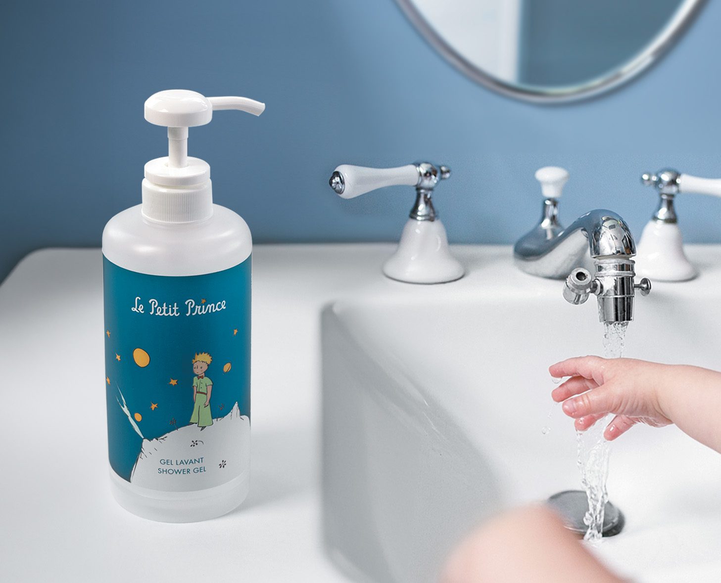 Eine Flasche „Le Petit Prince“ Duschgel steht auf einem Waschbecken neben einem laufenden Wasserhahn, während eine Kinderhand nach dem Wasser greift.
