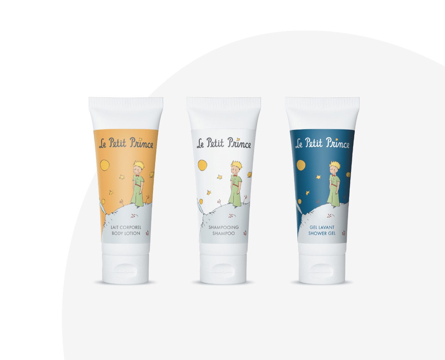 Drei Tuben mit Hautpflegeprodukten vonLe Petit Prince“: eine Körperlotion in einer gelben Tube, ein Shampoo in einer weißen Tube und ein Duschgel in einer dunkelblauen Tube, jeweils mit Illustrationen eines kleinen Jungen mit Sternen.