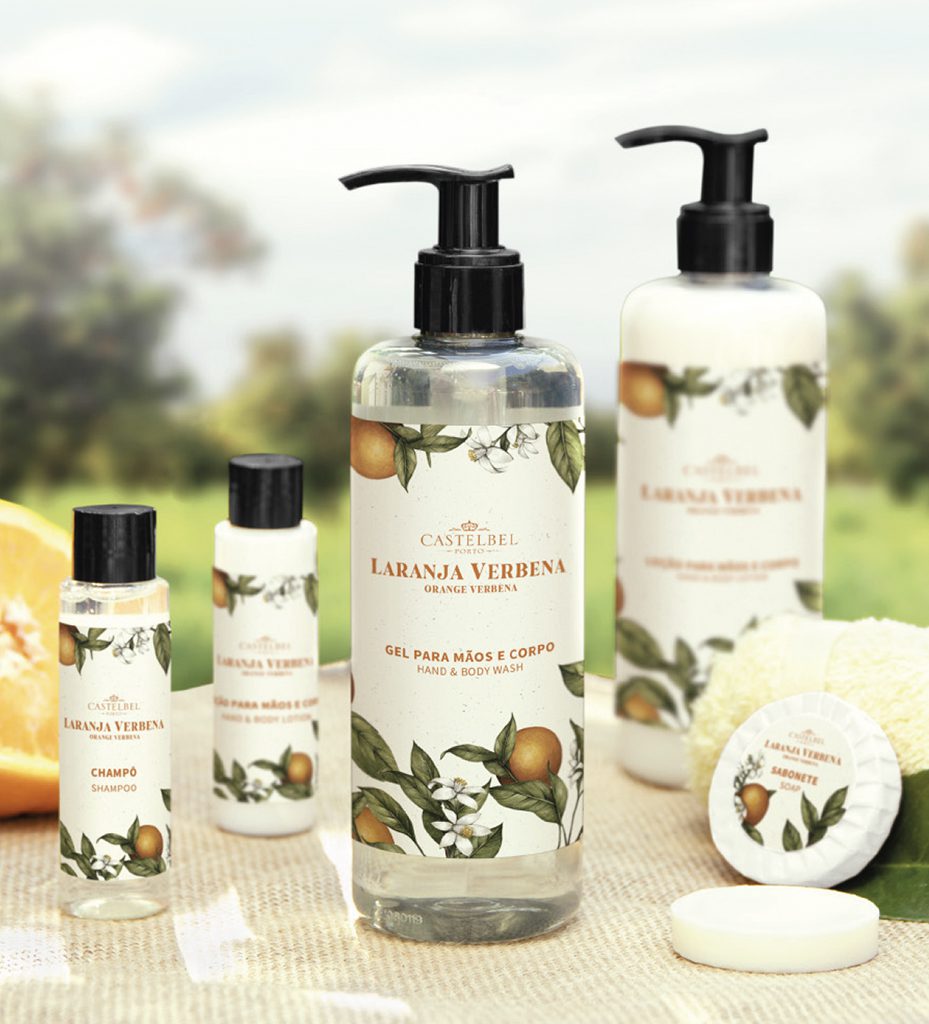 Una collezione di prodotti per la cura personale con l'etichetta "Laranja Verbena" (Verbena all'arancia), che comprende un flacone grande di sapone liquido per mani e corpo, un flacone di shampoo e uno scrub per il corpo, tutti decorati con motivi floreali.