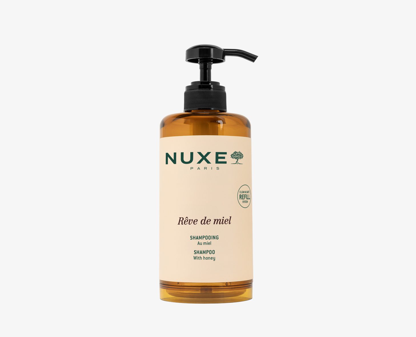 Μια φιάλη σαμπουάν NUXE Rêve de Miel με αντλία διανομής, με σχέδιο με θέμα το μέλι και ετικέτα που μπορεί να ξαναγεμιστεί. Η φιάλη είναι κεχριμπαρένια με κρεμ χρώματος ετικέτα.