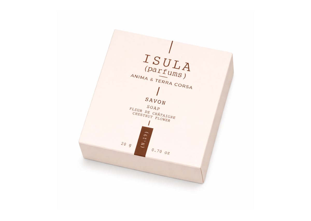 Una confezione di sapone rosa chiaro con la scritta "ISULA parfums) ANIMA &amp; TERRA CORSA" e le parole "SAVON" e "FLEUR DE CHâTAIGNER" stampate sopra, contenente 20 grammi di prodotto.