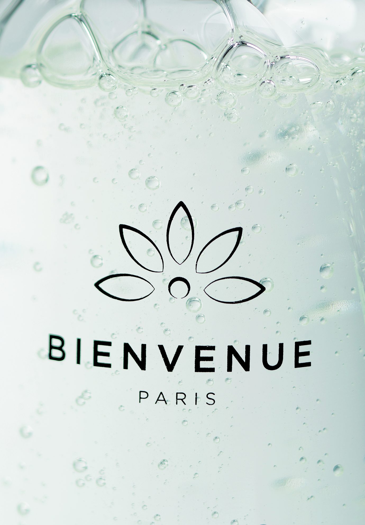 Nahaufnahme von Bienvenue Paris Duschgel mit Bläschen in der Flüssigkeit, die das Markenlogo hervorheben.