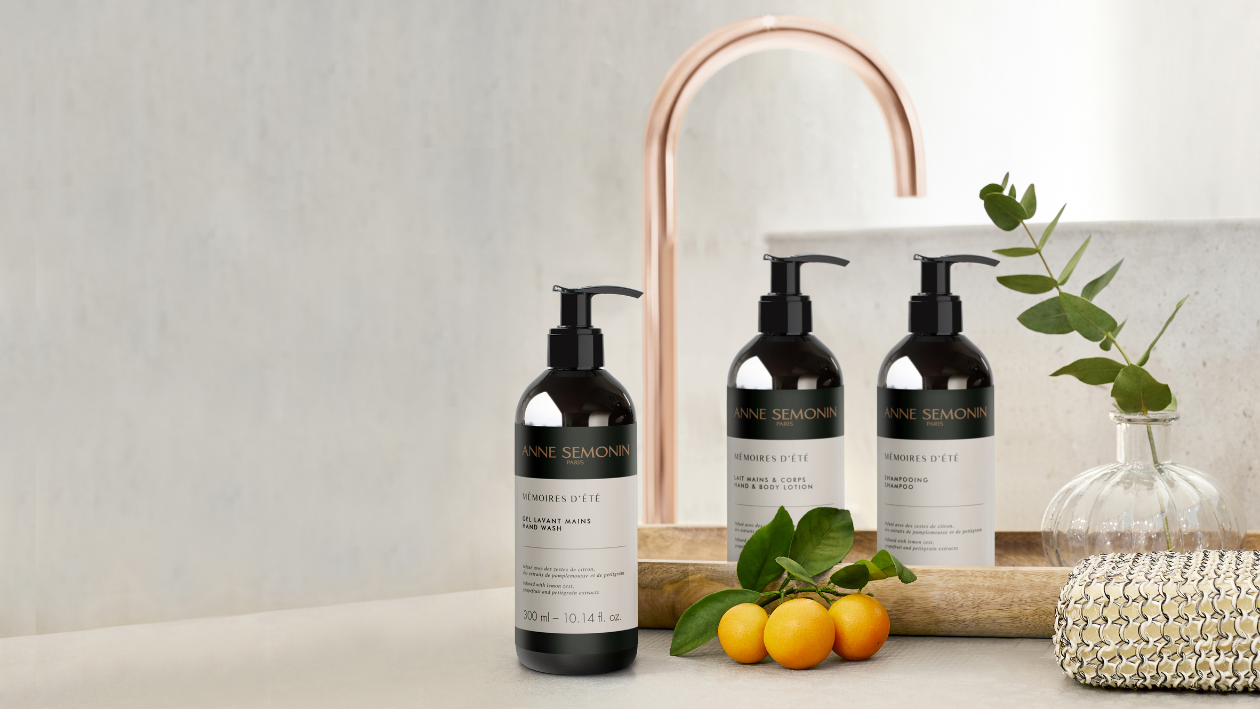 Anne Semonin „Mémoires d’Été“ Handseife, Körperlotion und Shampoo, präsentiert neben einem Waschbecken mit Zitrusfrüchten und Grünpflanzen.