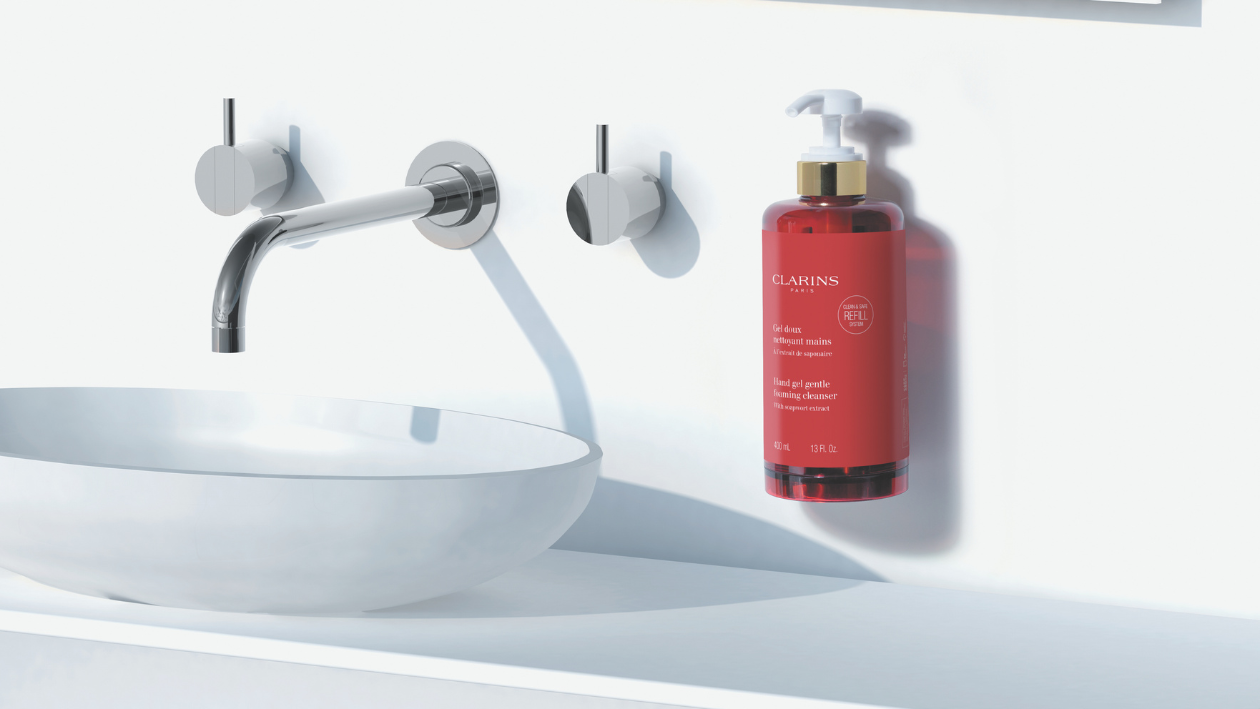 Clarins Eine Flasche Handseife von Clarins, die neben einem modernen Waschbecken angebracht ist, präsentiert in einem klaren, minimalistischen Badezimmer.