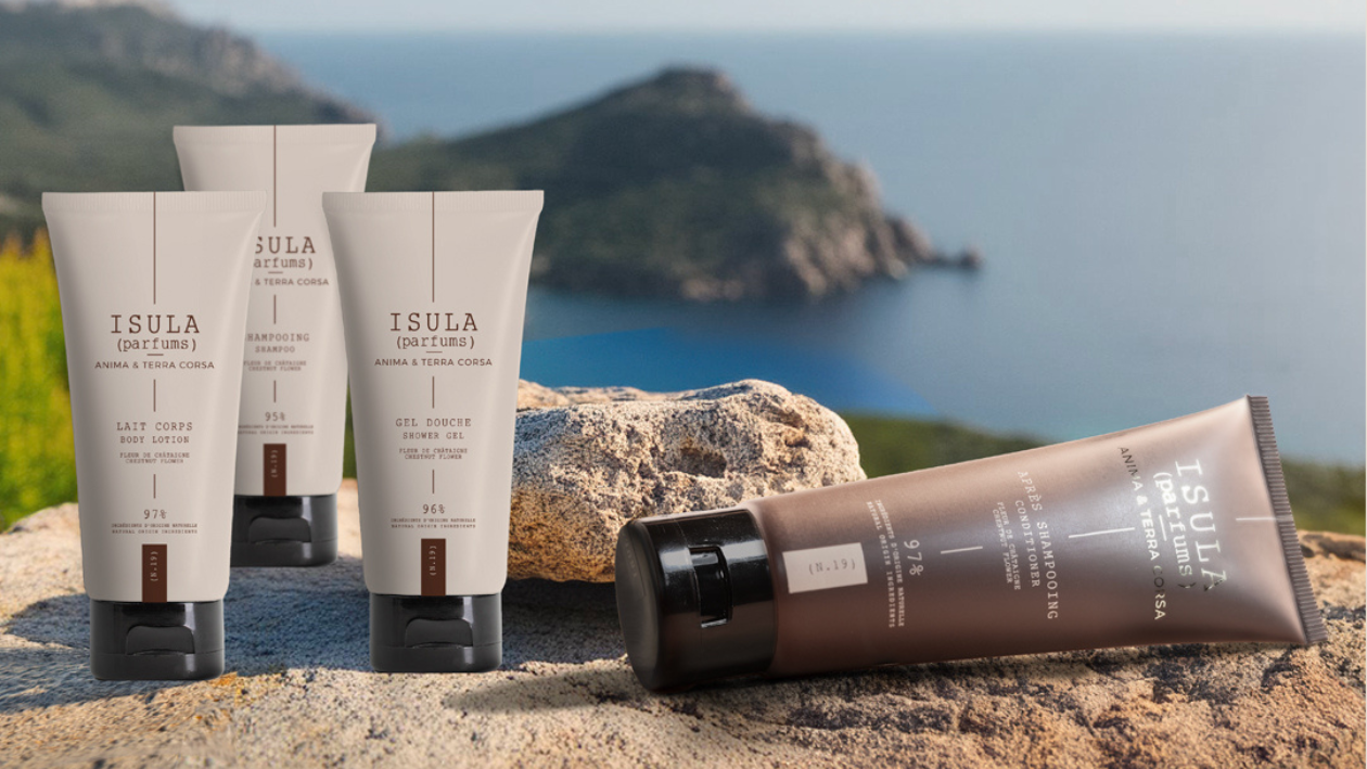 Isula Körperpflegeprodukte von Isula Parfums, darunter Shampoo, Duschgel, Lotion und Haarspülung, präsentiert auf Felsen mit Meerblick