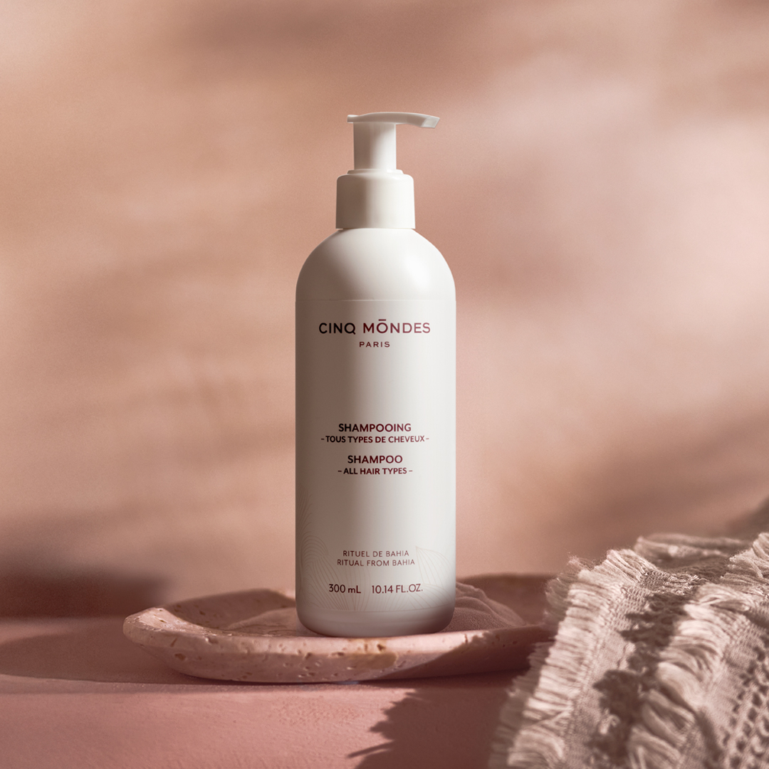 Cinq Mondes Paris-Shampooflasche mit Pumpspender auf einer Keramikschale, vor einem sanften beigen Hintergrund