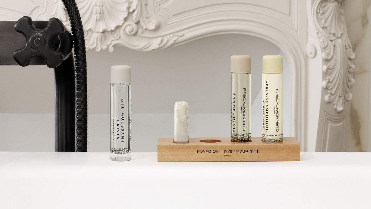 Pascal Morabito Duschgel, Shampoo und Haarspülung in Reisegröße, angeordnet auf einem Holztablett neben einer modernen Duscharmatur.