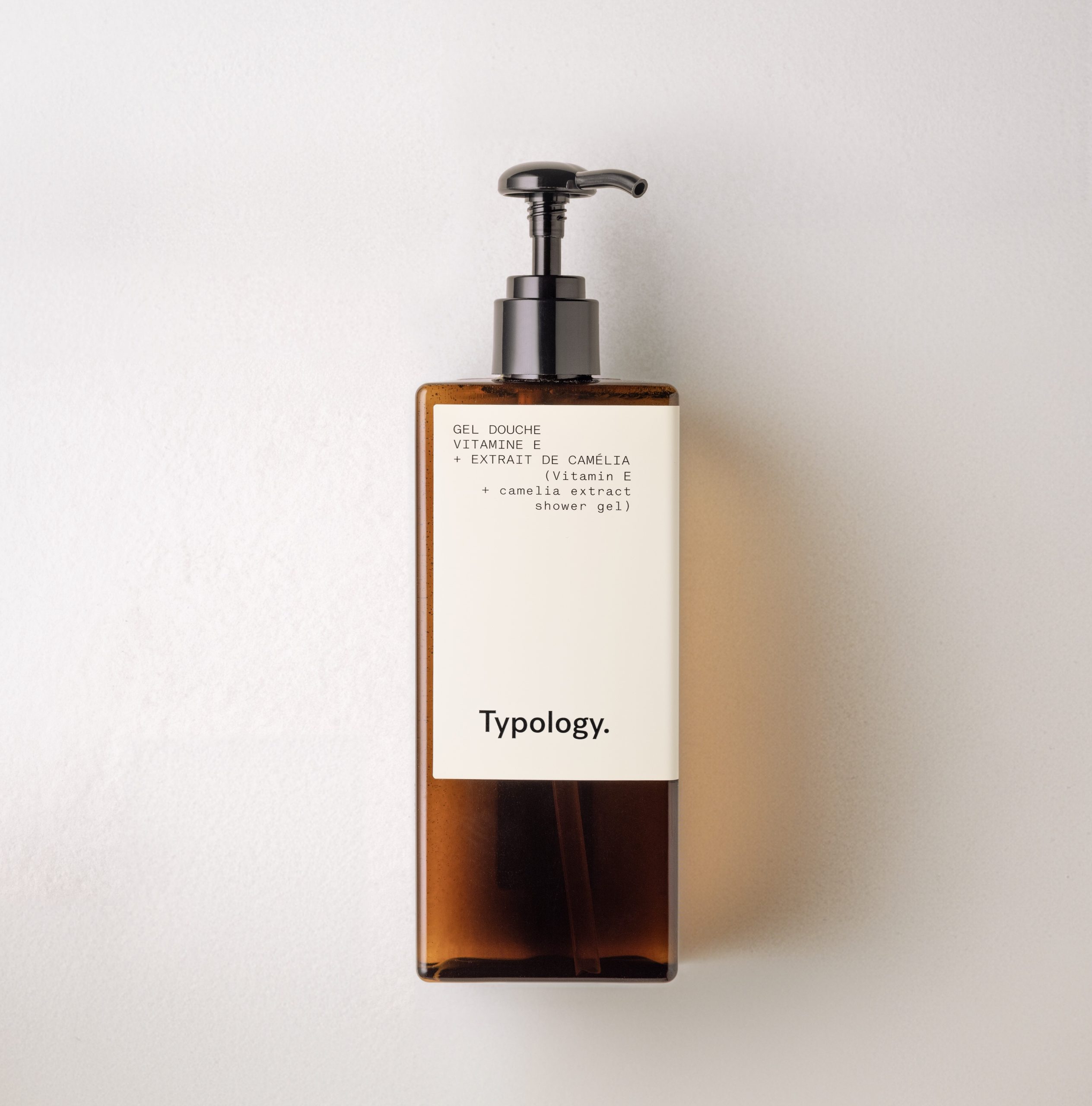 Typology Duschgel-Pumpflasche mit bernsteinfarbenem Design auf neutralem Hintergrund