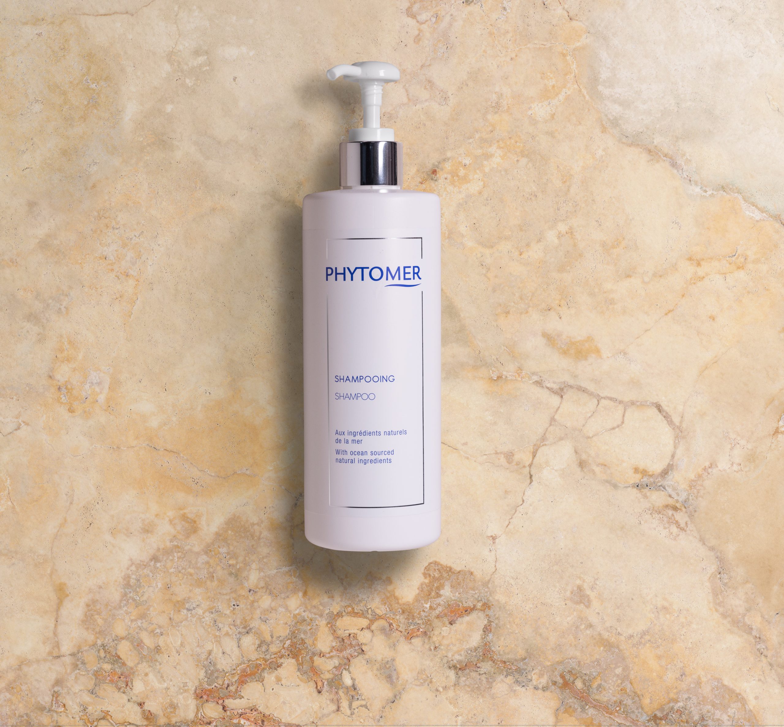 Phytomer Shampooflasche mit Pumpspender vor einem strukturierten Steinhintergrund.